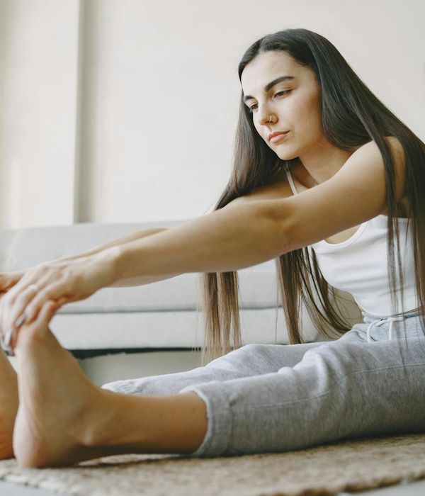 Woman performing a light stretching exercise in a bright, airy room.